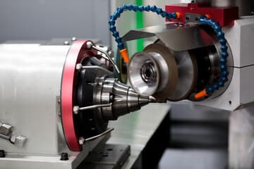 Close-up of a CNC machine with a drill bit positioned near a metal workpiece.